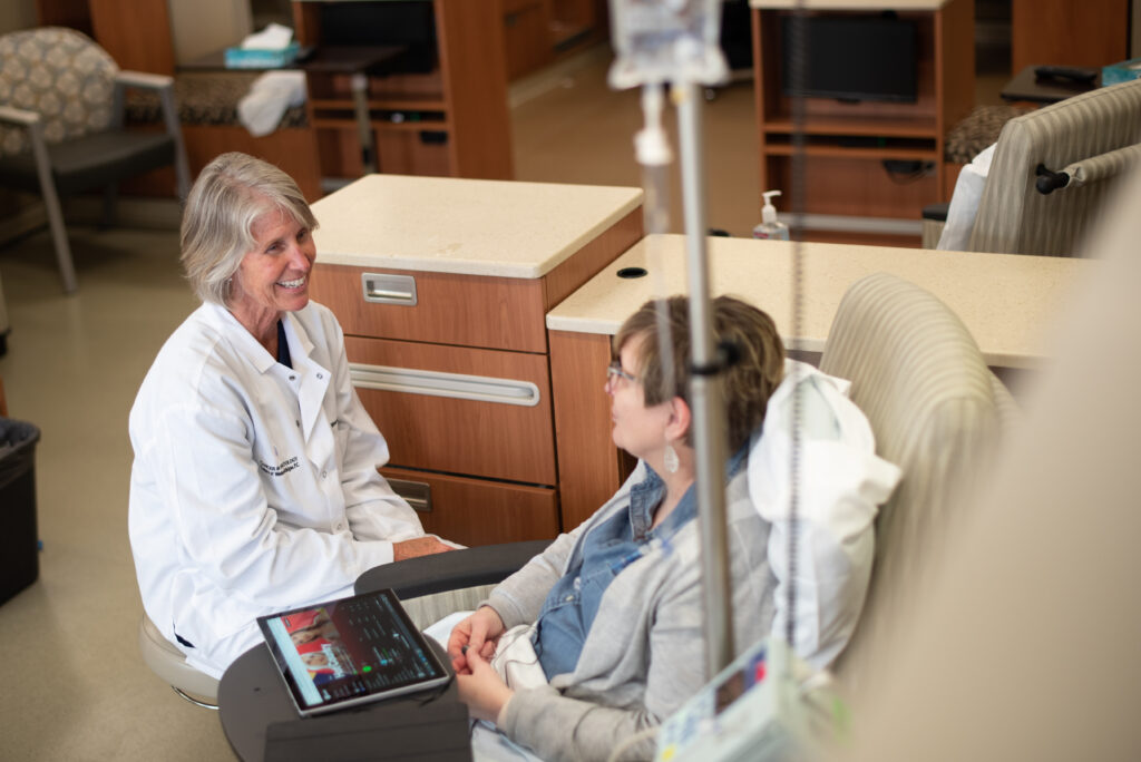 Doctor sitting with patient connected to intravenous drip